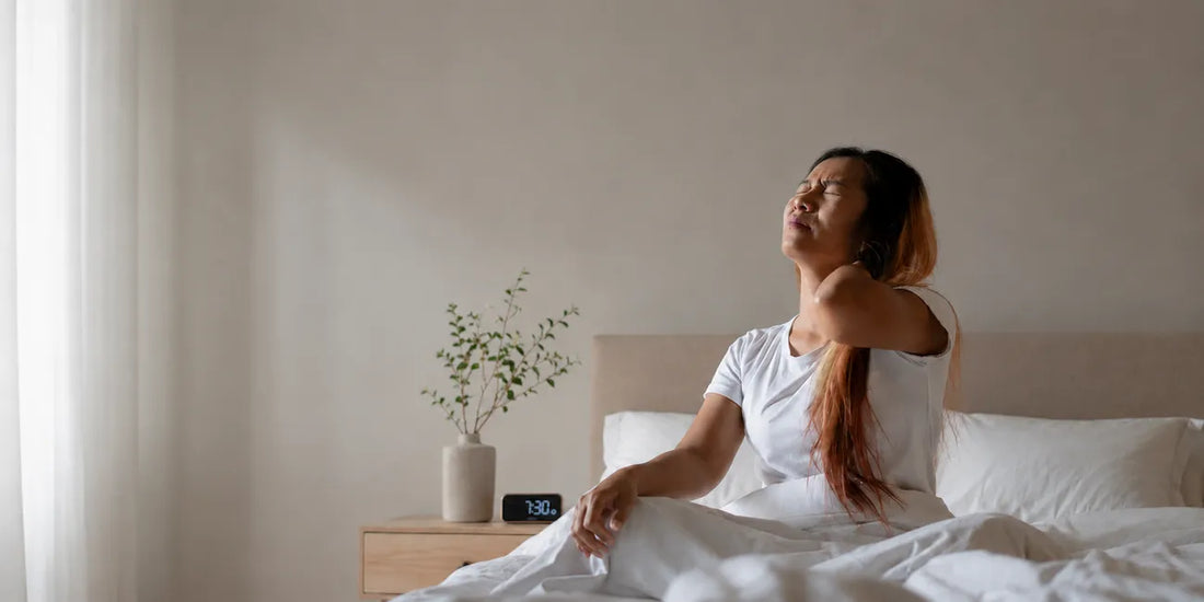 Woman sitting in bed holding her neck in pain
