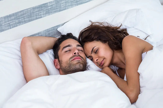Man and woman cuddling together in white bedding